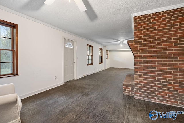 entrance foyer featuring brick wall, dark wood-type flooring, a textured ceiling, and crown molding