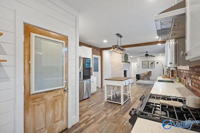 kitchen featuring white cabinetry, ceiling fan, brick wall, stovetop, and pendant lighting