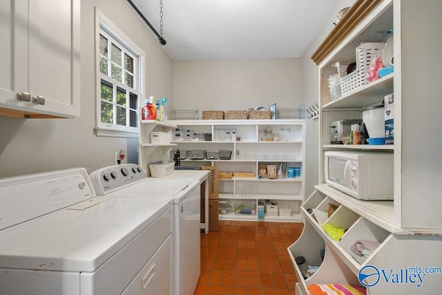 laundry area featuring separate washer and dryer, a textured ceiling, and cabinets