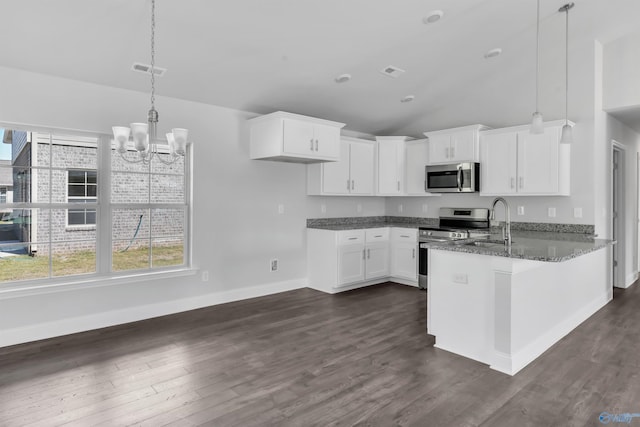 kitchen with stainless steel appliances, decorative light fixtures, white cabinetry, dark stone counters, and dark wood-type flooring