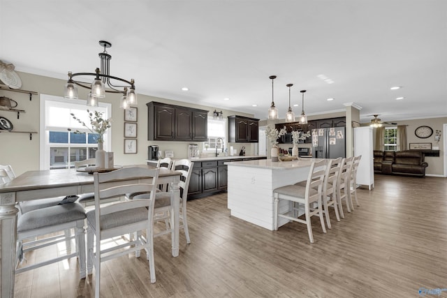 kitchen with dark brown cabinets, ceiling fan with notable chandelier, a kitchen island, and hardwood / wood-style floors