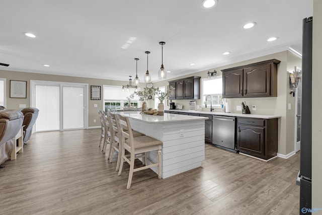 kitchen with light hardwood / wood-style flooring, hanging light fixtures, dishwasher, a kitchen breakfast bar, and a kitchen island