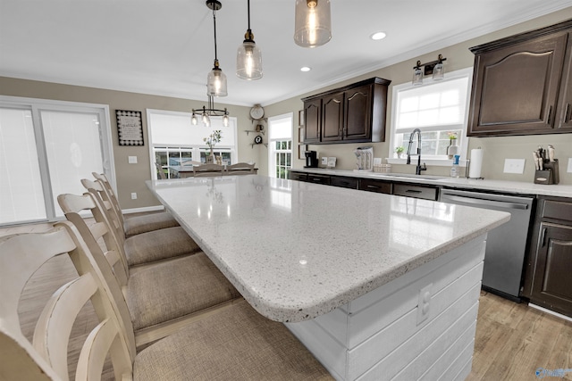 kitchen with hanging light fixtures, stainless steel dishwasher, a center island, light hardwood / wood-style floors, and sink