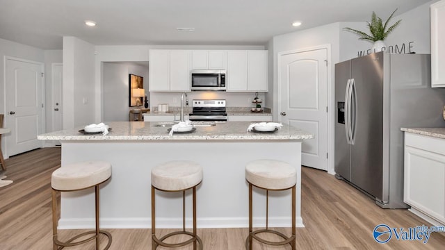 kitchen with appliances with stainless steel finishes, sink, white cabinetry, and a center island with sink