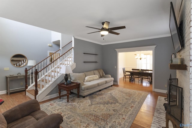 living room with ceiling fan with notable chandelier, hardwood / wood-style flooring, and ornamental molding