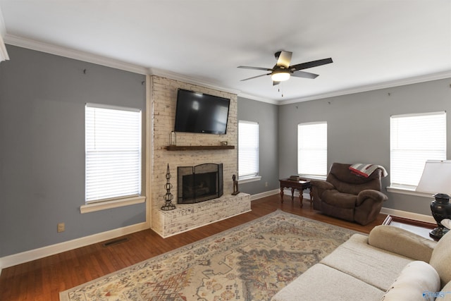 living room featuring ceiling fan, dark hardwood / wood-style flooring, crown molding, and a brick fireplace