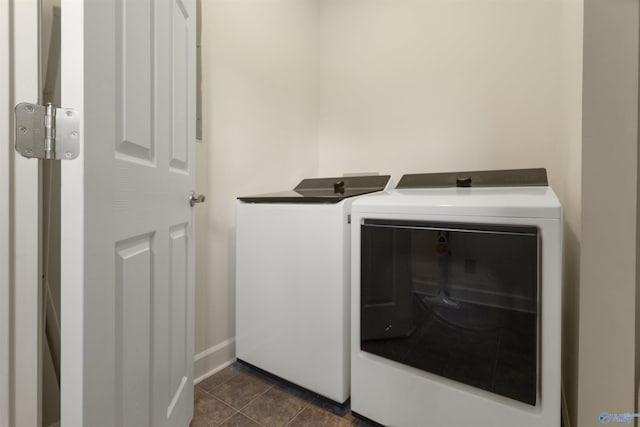 laundry area with dark tile patterned flooring and washing machine and clothes dryer