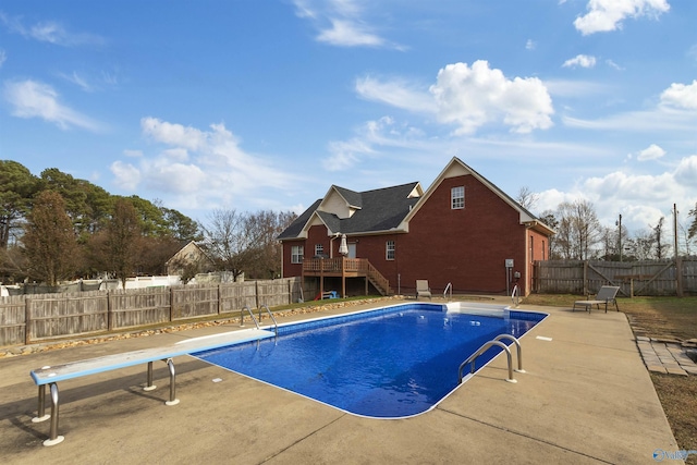 view of swimming pool featuring a patio, a deck, and a diving board