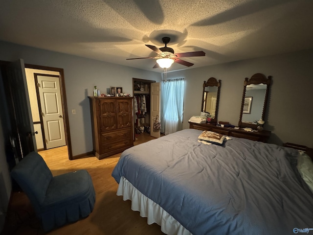 bedroom with light wood-style flooring, a textured ceiling, baseboards, and ceiling fan