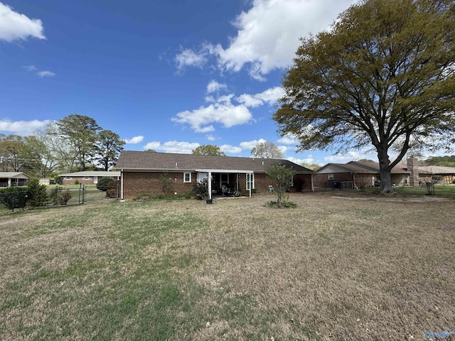 rear view of property with brick siding, fence, and a lawn