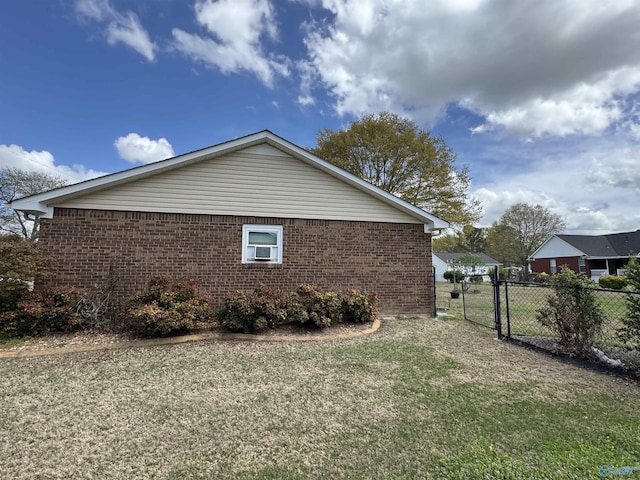view of side of home featuring brick siding, fence, a gate, and a lawn