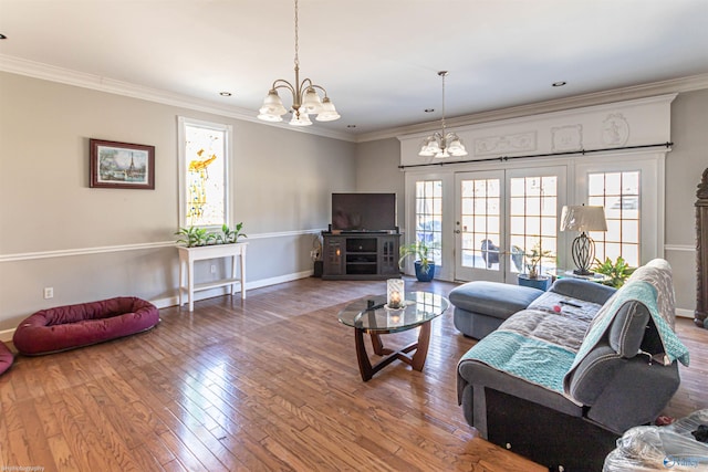 living room featuring crown molding, wood-type flooring, french doors, and a notable chandelier