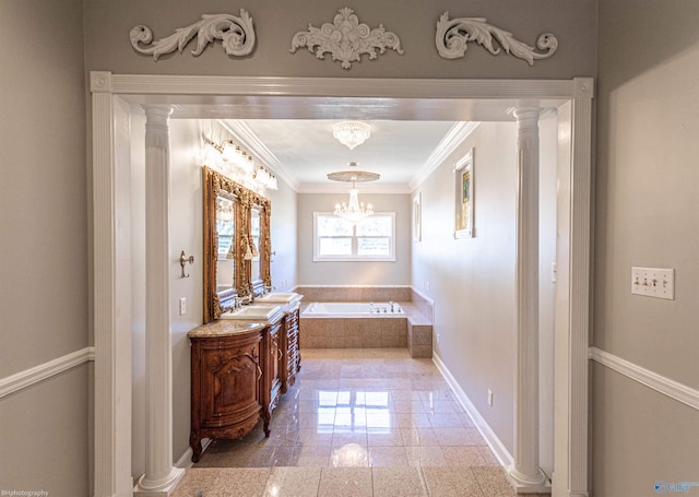 bathroom featuring tiled tub, sink, a notable chandelier, and ornate columns