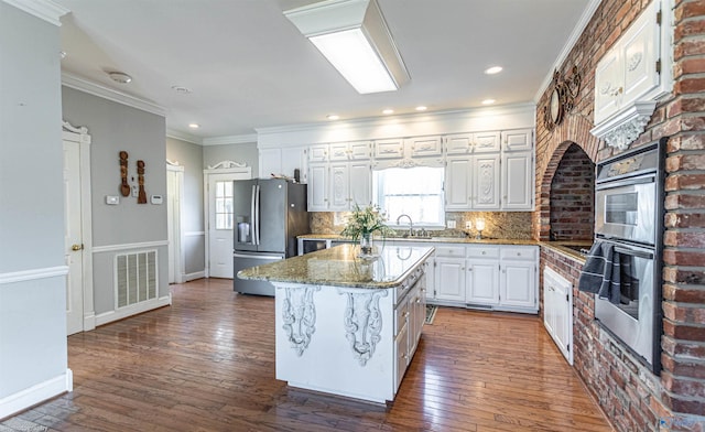 kitchen with backsplash, a center island, stainless steel refrigerator with ice dispenser, light stone countertops, and white cabinets