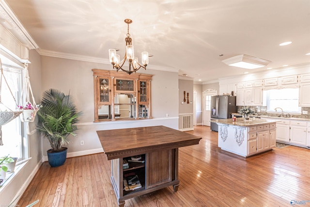 kitchen featuring white cabinetry, a center island, light stone countertops, and stainless steel refrigerator with ice dispenser