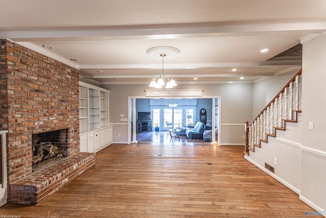 interior space with hardwood / wood-style floors, a fireplace, a notable chandelier, beam ceiling, and built in shelves