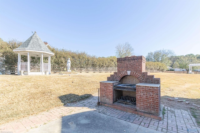 view of patio with an outdoor brick fireplace and a gazebo