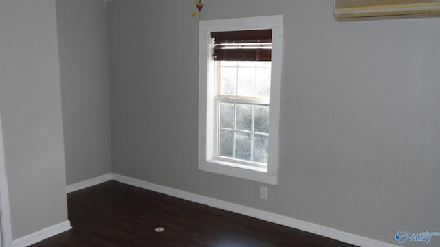 unfurnished room with a wall mounted AC and dark wood-type flooring