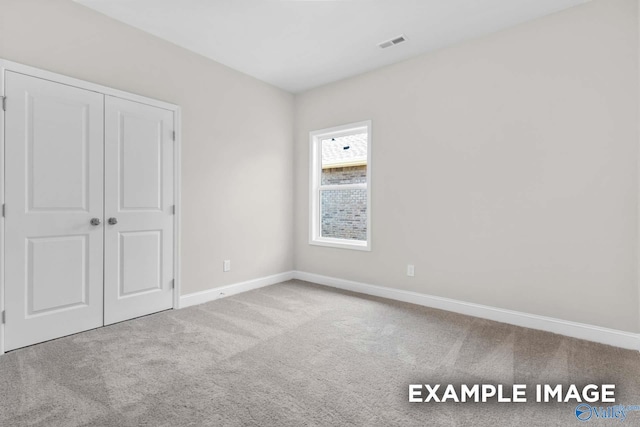 unfurnished bedroom featuring a closet and light colored carpet