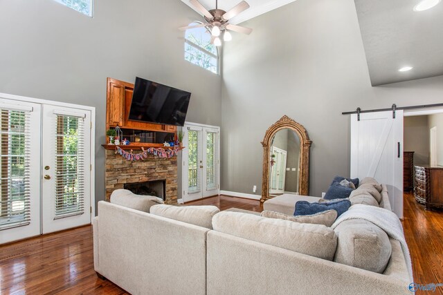 living room featuring a fireplace, light hardwood / wood-style flooring, ceiling fan, and high vaulted ceiling