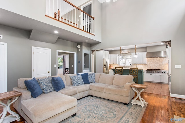 living room with hardwood / wood-style floors, sink, and a towering ceiling