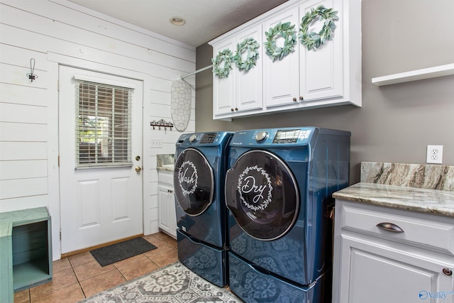 laundry room with light tile patterned floors, washing machine and clothes dryer, wooden walls, and cabinets