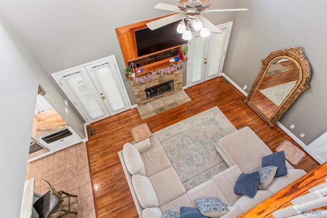 living room with hardwood / wood-style floors, french doors, a high ceiling, a fireplace, and ceiling fan