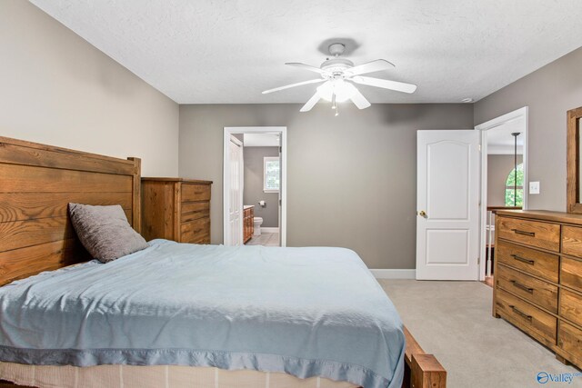 bedroom featuring ceiling fan, multiple windows, ensuite bath, and light carpet