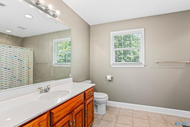 bathroom with tile patterned flooring, plenty of natural light, toilet, and vanity