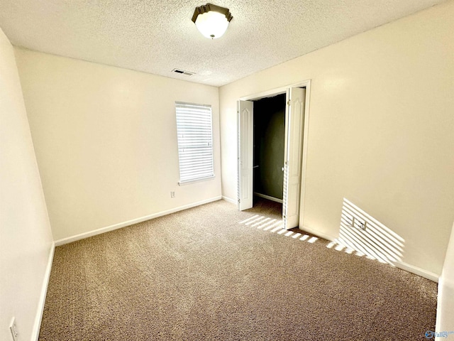 spare room featuring carpet and a textured ceiling