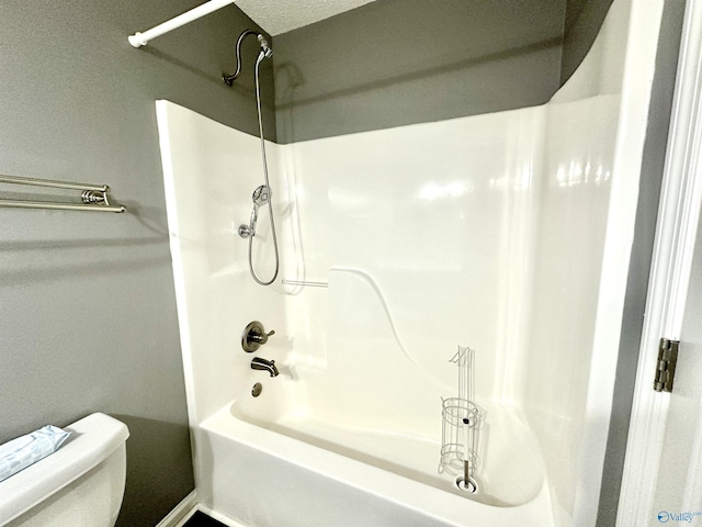 bathroom featuring toilet, shower / tub combination, and a textured ceiling