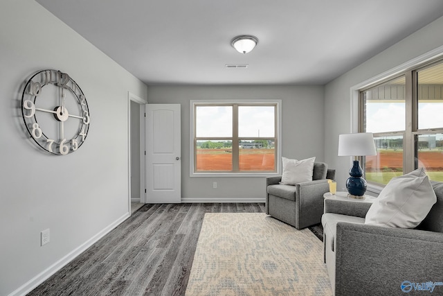 sitting room featuring dark wood-style flooring, visible vents, and baseboards