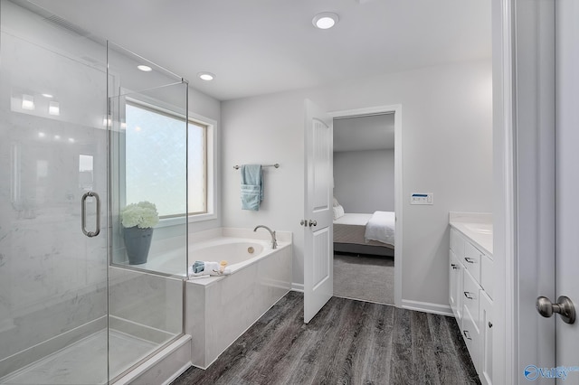 bathroom featuring baseboards, connected bathroom, wood finished floors, a garden tub, and a shower stall