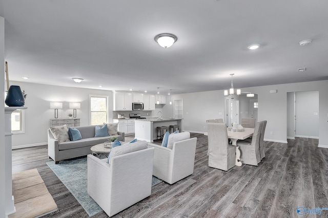 living room with sink, a chandelier, and wood-type flooring