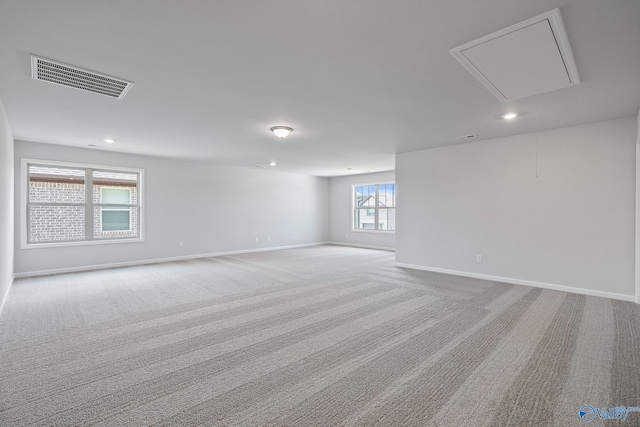 unfurnished room with light carpet, attic access, visible vents, baseboards, and recessed lighting