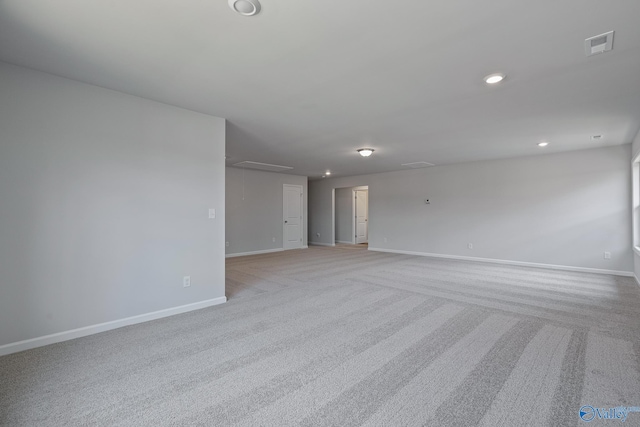 empty room with light carpet, attic access, visible vents, baseboards, and recessed lighting