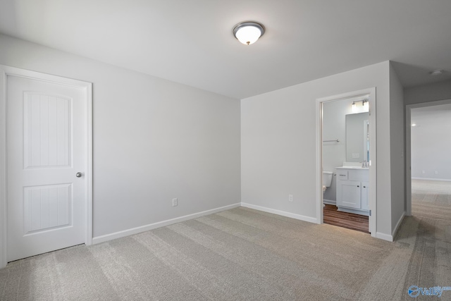 unfurnished bedroom featuring ensuite bathroom and carpet floors