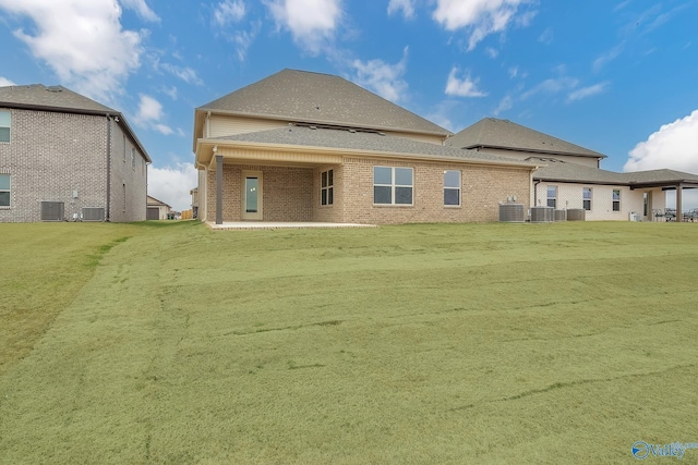 rear view of property with a patio area, central AC, a lawn, and brick siding