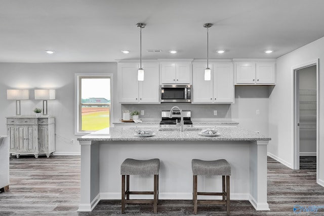 kitchen with white cabinets, light stone countertops, stainless steel appliances, and a sink