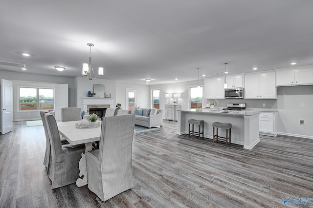 dining area featuring sink, wood-type flooring, and a chandelier