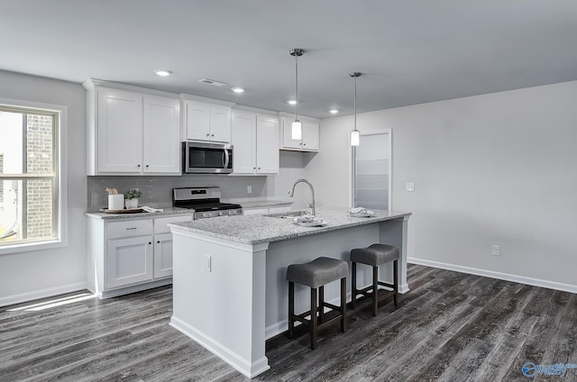 kitchen with stainless steel appliances, a sink, a kitchen island with sink, and white cabinetry