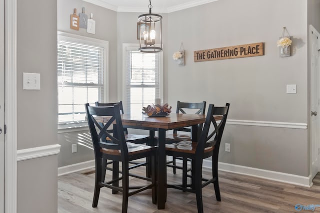 dining space featuring ornamental molding, a chandelier, and hardwood / wood-style flooring