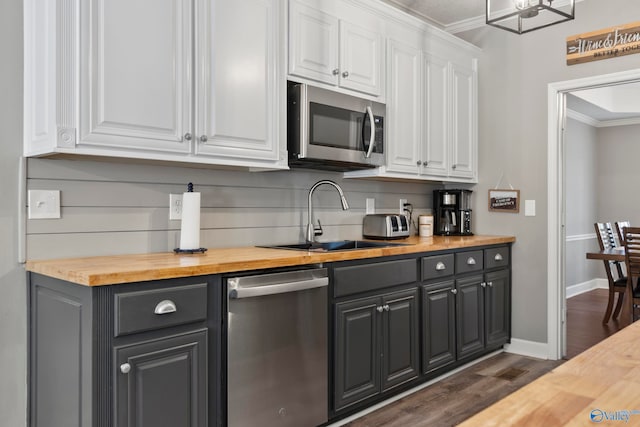 kitchen with white cabinetry, butcher block counters, appliances with stainless steel finishes, dark hardwood / wood-style flooring, and ornamental molding