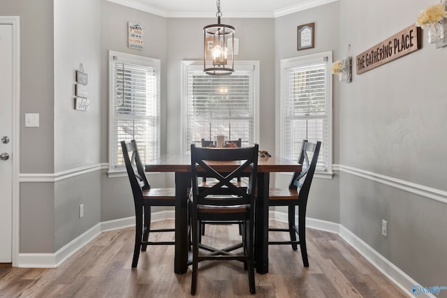 dining space with an inviting chandelier, hardwood / wood-style flooring, crown molding, and a healthy amount of sunlight