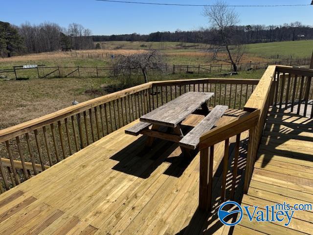 wooden deck featuring fence, outdoor dining area, and a rural view