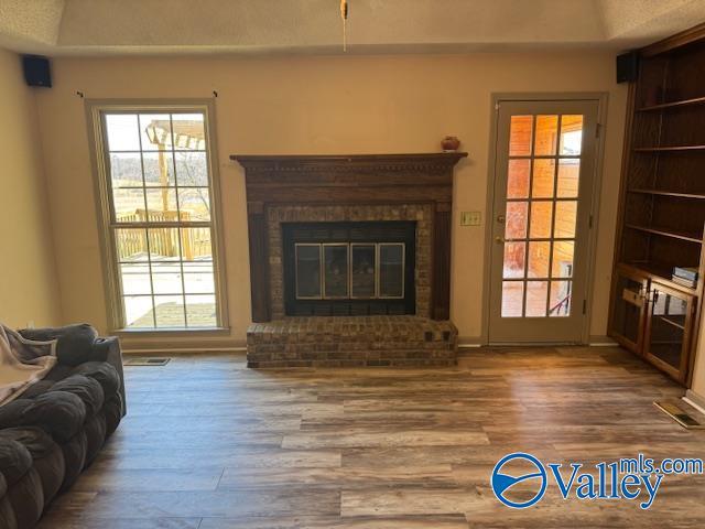 living area featuring plenty of natural light, a fireplace, and wood finished floors