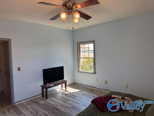 bedroom featuring ceiling fan, a textured ceiling, and wood finished floors