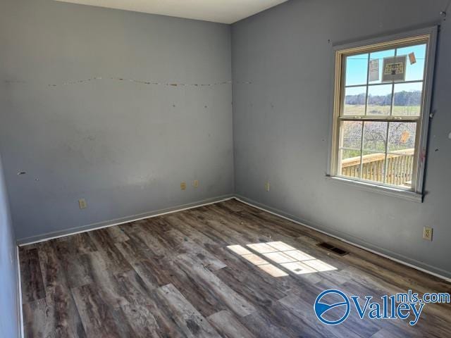 unfurnished room with baseboards, visible vents, and wood finished floors