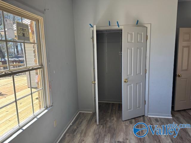 unfurnished bedroom with a closet, baseboards, and wood finished floors