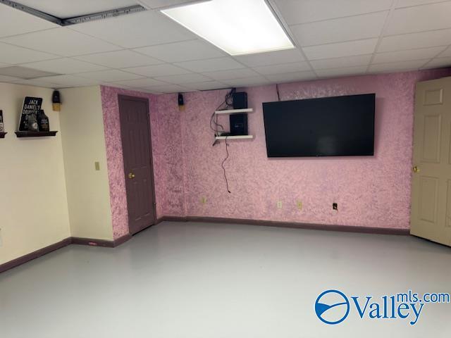 finished basement featuring a drop ceiling and baseboards